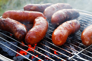 Grilling sausages on barbecue grill