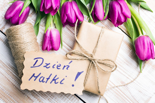 Mother's Day card and a bouquet of beautiful tulips on wooden background, with Polish words "Mother's Day"