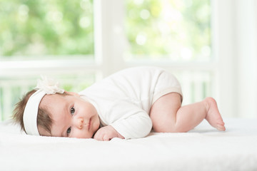 Obraz na płótnie Canvas Baby girl child lying down on white blanket