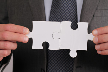 Business solutions, partnership concept. Businessman holding two pieces of a blank puzzle
