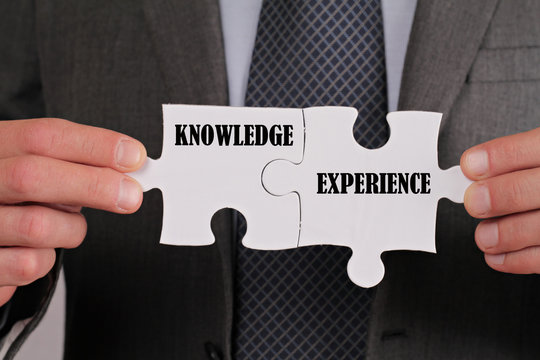 Business Success Concept. Connection Between Knowledge And Experience, Businessman Holding Two Pieces Of A Puzzle Close Up