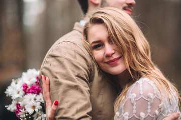 Obraz premium Romantic fairytale wedding couple kissing and embracing in pine forest near retro car.