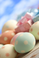 Colored Easter eggs in pastel colors and gift boxes on blue sky