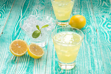 lemonade or limonchello in glasses, sherbet glass with ice cubes decorated by mint leaf, lemon...