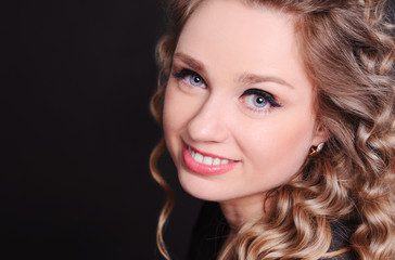 Obraz premium Close up portrait of young attractive woman 20-24 year old smiling over black. Looking at camera. 