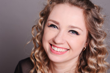 Fototapeta premium Laughing young woman close up. Beautiful girl 20-25 year old smiling over gray.