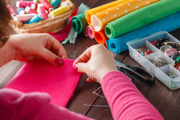 closeup of woman hands sewing pink hamdmade toy