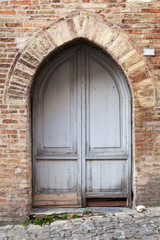Fototapeta na wymiar Old gray wooden door with arch in brick wall