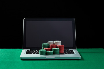 Casino chips on keyboard notebook at green table. 