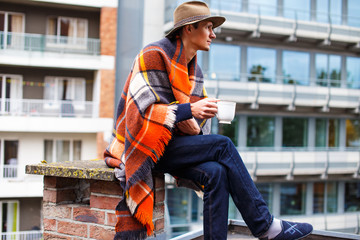 A man covered with blanket drinking hot tea.