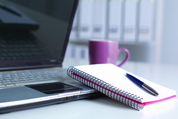 Office table with blank notepad and laptop 