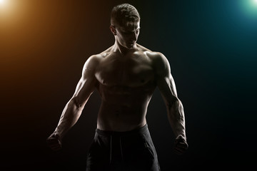 Fototapeta na wymiar Sexy muscular man posing with naked torso on black background