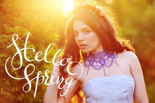 Beautiful happy young woman enjoying smell in a flowering spring garden with letters Hello sprint