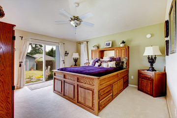 Master bedroom with grey carpet, ceiling fan, and purple bedding