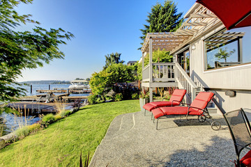 Fototapeta premium Waterfront back yard, Furnished back patio with red chairs, and