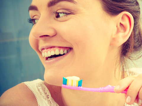 woman brushing cleaning teeth. Girl with toothbrush in bathroom.