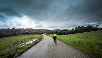 man on a bicycle ride along a mountain road during a storm