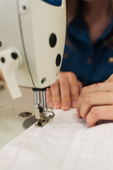 seamstress sews clothes and put thread in needle. Workplace of tailor - sewing machine, rolls of of thread, fabric