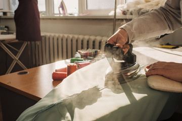 dressmaker stroked the fabric with steam iron