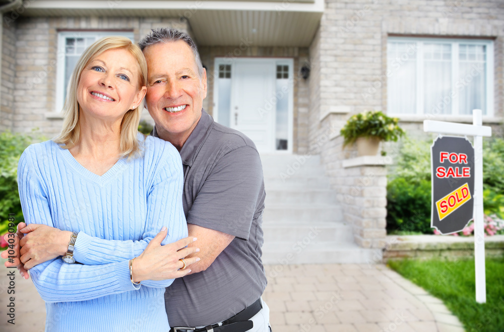 Poster happy senior couple near new house.