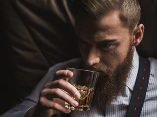 Fotobehang Cheerful bearded businessman is drinking expensive whisky © Yakobchuk Olena
