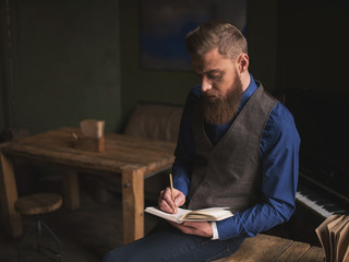 Cheerful bearded author is writing a poem