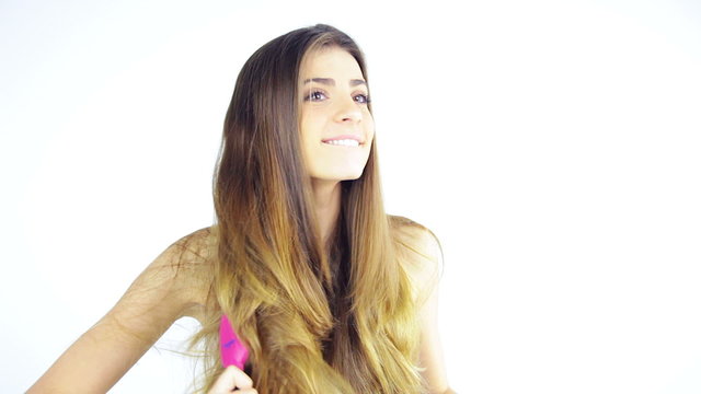 Happy beautiful woman brushing long amazing hair with 4 brushes