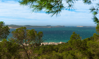 Fototapeta na wymiar Panoramic hill side view from St Antoni de Portmany, Ibiza, into Balearic sea on a clearing day in November, featuring the oft viewed Conejera islands.