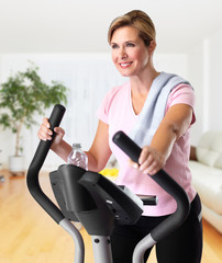 Mature woman doing exercise on elliptical trainer.
