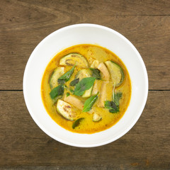 The delicious homemade Thai green curry with pork (Gang Keaw Wan) in white bowl on old wooden planks.