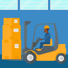 Warehouse worker moving load by forklift truck.