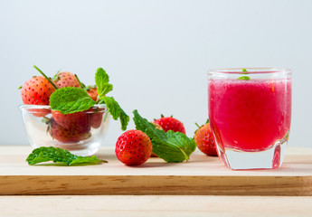 Fresh red strawberries juice in transparent glass for drink on w