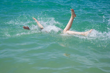 Legs and hands in waves of turquoise sea