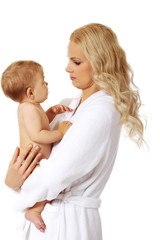 Young smiling mother in bathrobe holds her baby