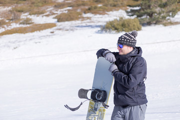 Fototapeta na wymiar Smiling man in hat and sunglasses with snowboard