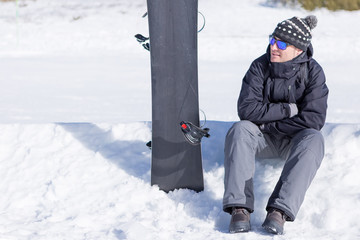 Fototapeta na wymiar Snowboarder in sunglasses sitting on snow