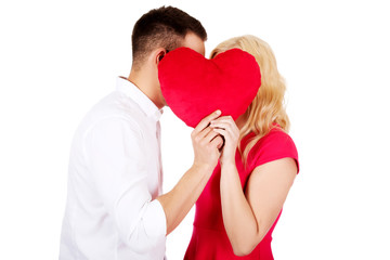 Young couple whispering behind the pillow