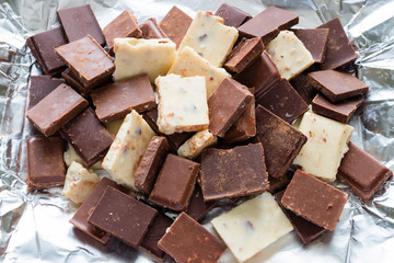 slices of different chocolate sprinkled with cocoa on a foil