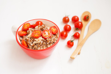 buckwheat cereal with tomatoes in a bowl on a table, selective focus