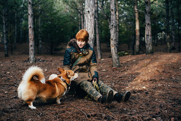 Naklejka na ściany i meble redhead girl walking with welsh corgi dog in the forest