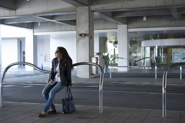 Obraz premium Young woman wearing a leather jacket is a friend outside waiting