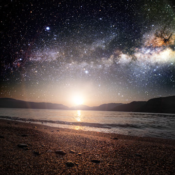 sun on a background star sky reflected in the sea. Elements of this image furnished by NASA