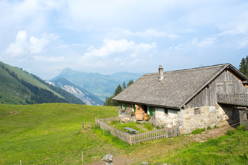 Old rustic house in the alps in Austria in clear weather with green fields and cloudy skies