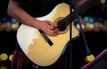 Naklejka premium Guitarist playing acoustic guitar with blur lights background