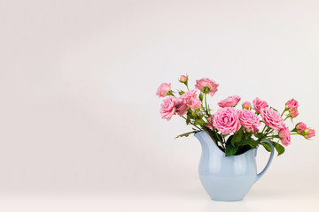 Fototapeta na wymiar Pink flowers in blue jug. Roses in jug.