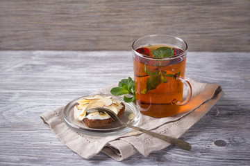 Mint tea and cake with cream and almond petals on a wooden surface, selective focus 