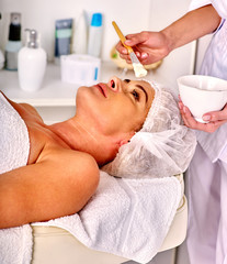 Obraz na płótnie Canvas Woman with close up middle-aged take facial and neck clay mask in spa salon.