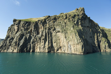 Rock and turquoise sea at the port of Vestmannaeyjar. On the rock thousands of birds nest.