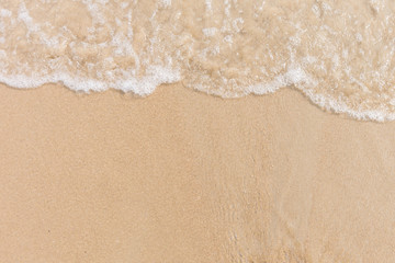 Fototapeta na wymiar Soft wave of the sea on the sandy beach with white clean foam. Copy space