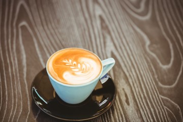 Cup of cappuccino with coffee art on wooden table